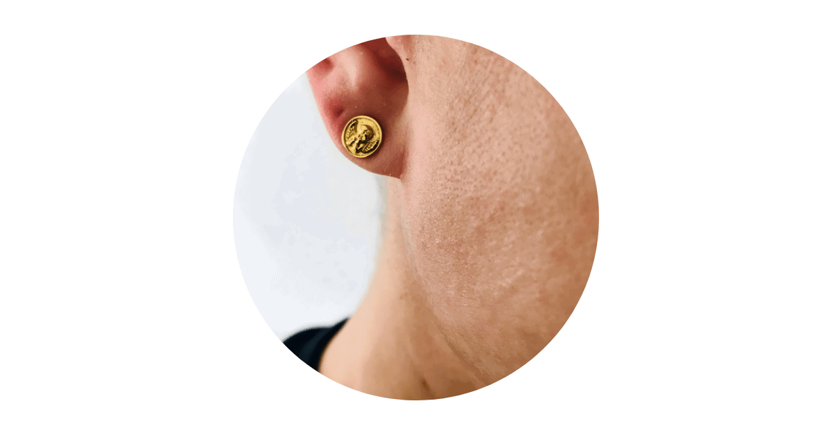 a man's ear adorned with a gold stud earring.