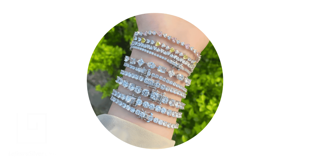 a person's wrist stacked with different tennis bracelets. 