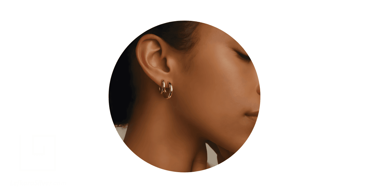 a woman wearing double gold hoop earrings.