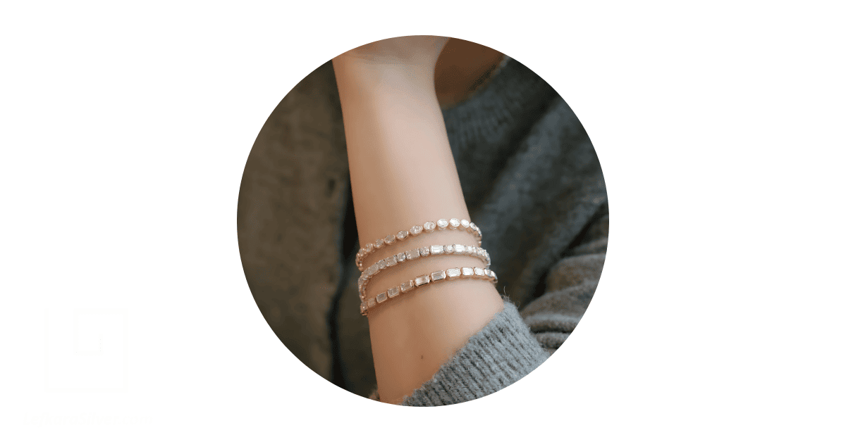 a person's wrist adorned with gold tennis bracelets. 