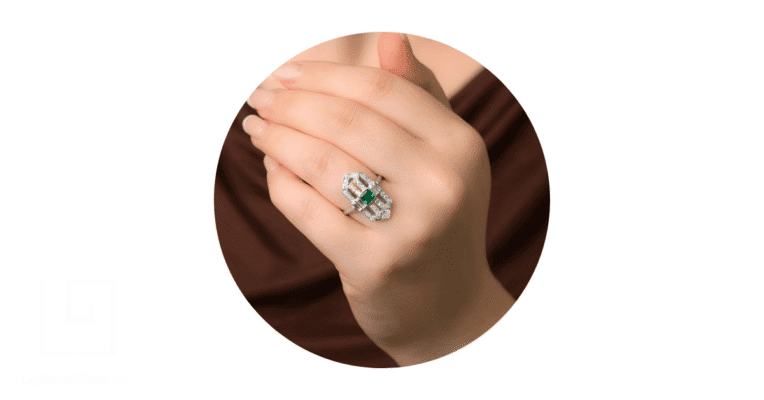 a woman's finger adorned with a unique emerald engagement ring.