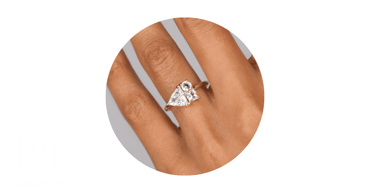 a person's finger adorned with a trillion-shaped engagement ring.
