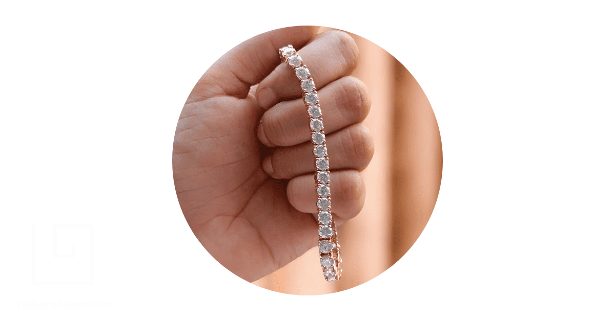 a person's hand holding a tennis bracelet. 