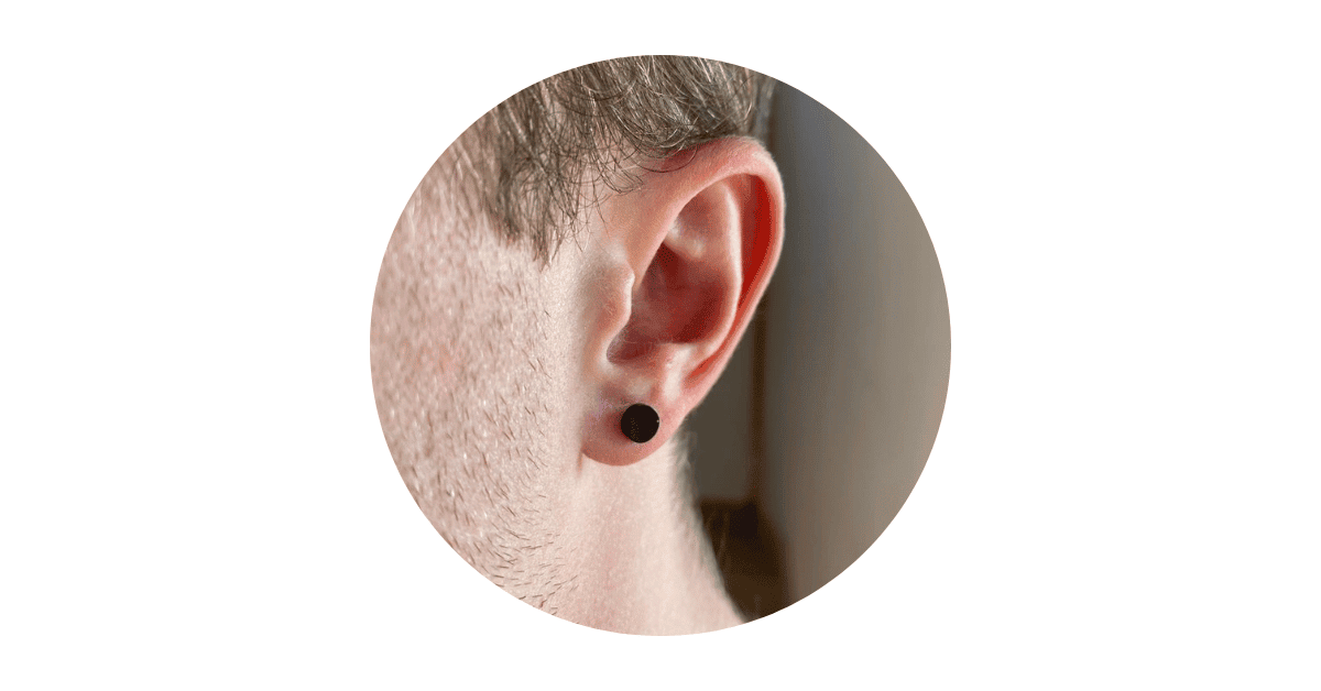 a man's ear adorned with a black stud earring.