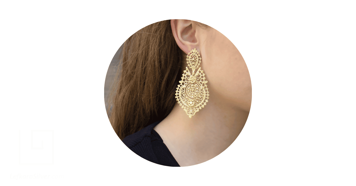 a woman's ear adorned with a gold filigree earring.