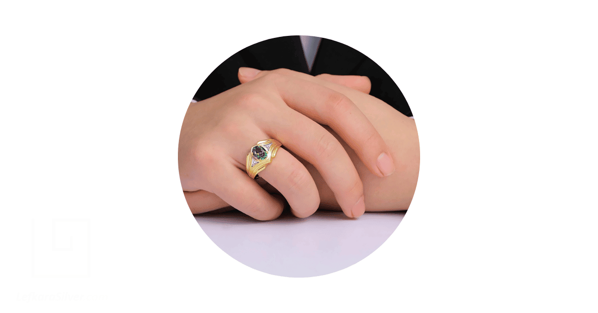 a man's finger adorned with a gold ring with a gemstone.