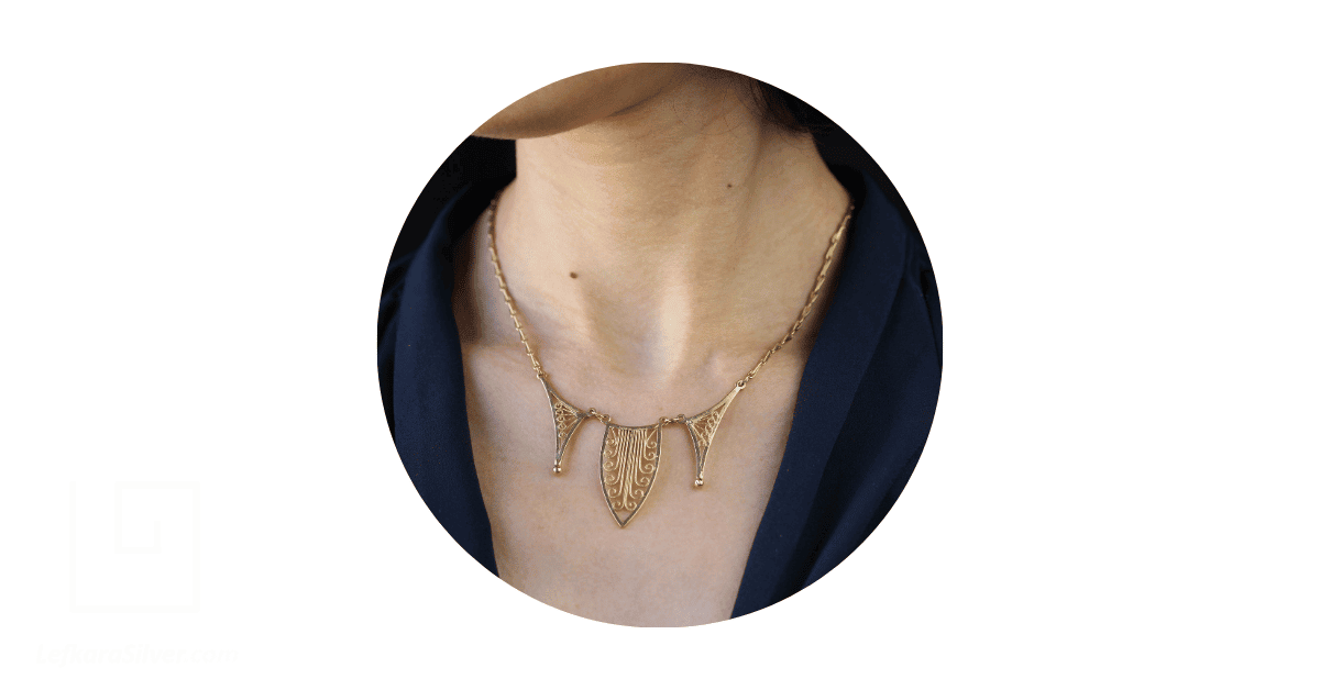 a woman's neck adorned with a gold filigree necklace.