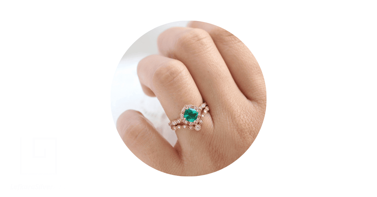 A woman's finger adorned with an emerald diamond wedding ring. 