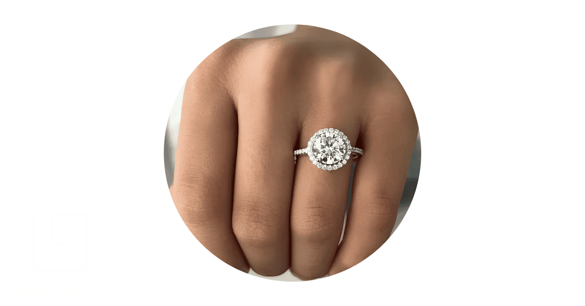 a person's fingers showing a white-gold ring with diamonds on one of them.