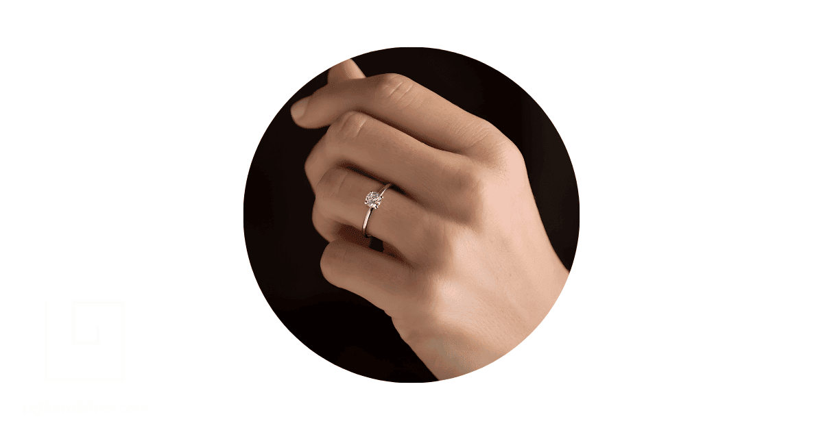 a person's finger adorned with a white gold ring.