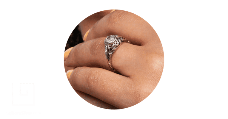 a person's finger adorned with a filigree wedding band.