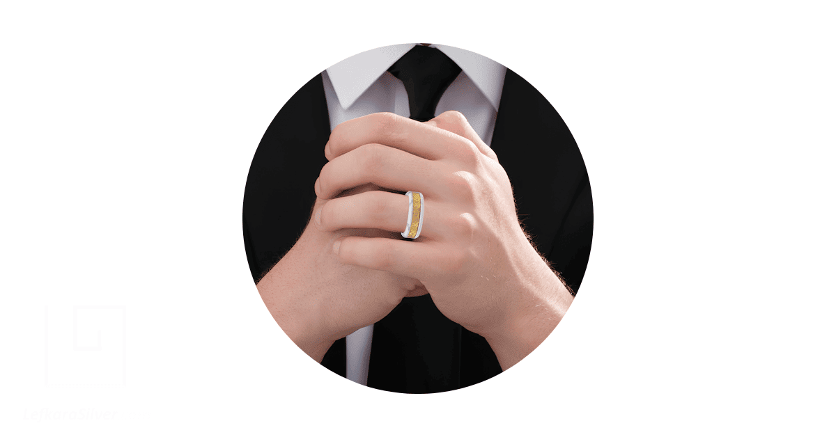 a man's clasped hands with a filigree wedding band on his finger.