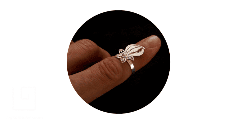 a person's finger adorned with a sterling silver filigree ring.
