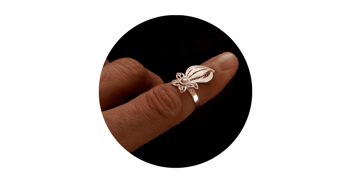 a person's finger adorned with a sterling silver filigree ring.