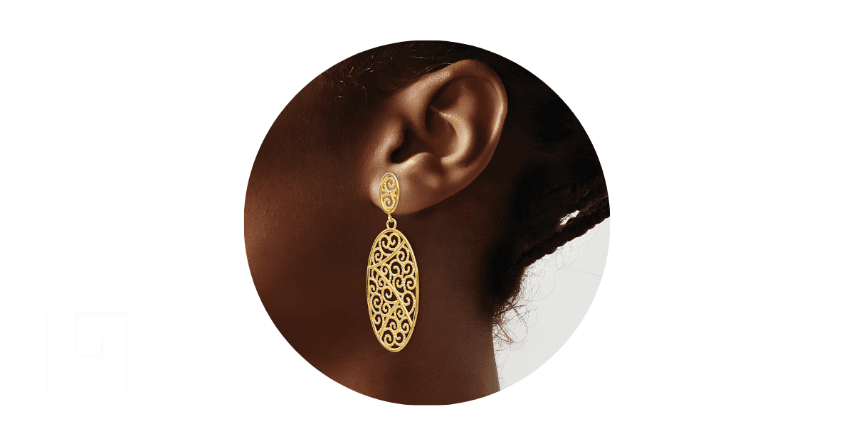 a person's ear adorned with a gold filigree drop earring.