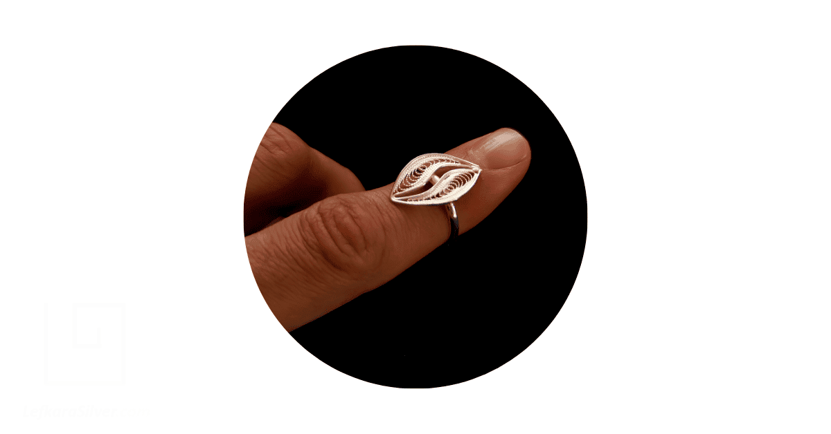 a person's finger adorned with a silver filigree ring from Lefkara Silver.