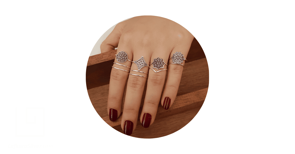 a person's fingers adorned with stacks of sterling silver filigree rings.