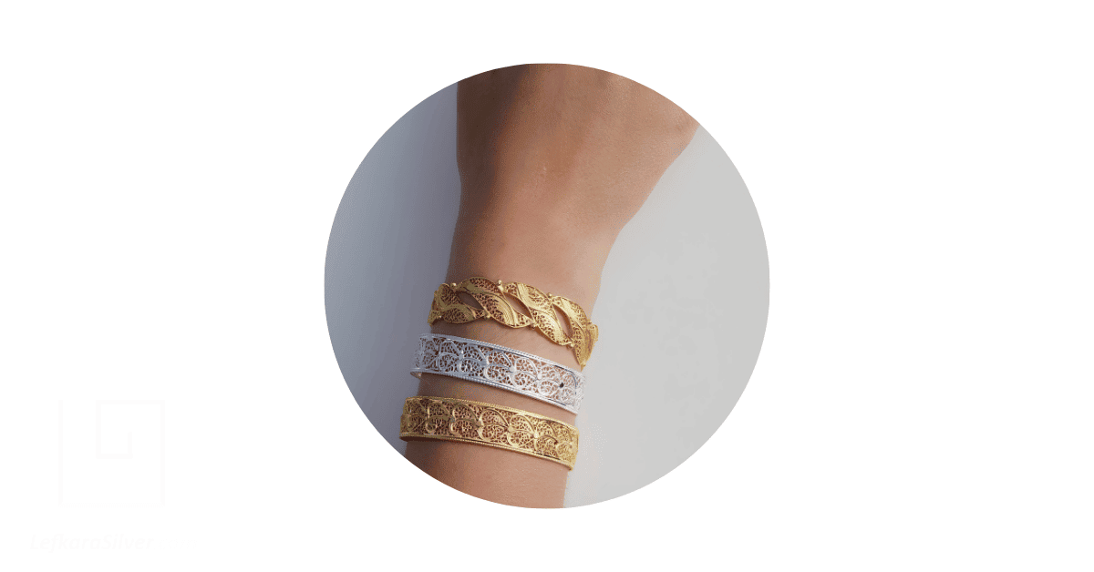 A person's hand adorned with a stack of French filigree bangles.
