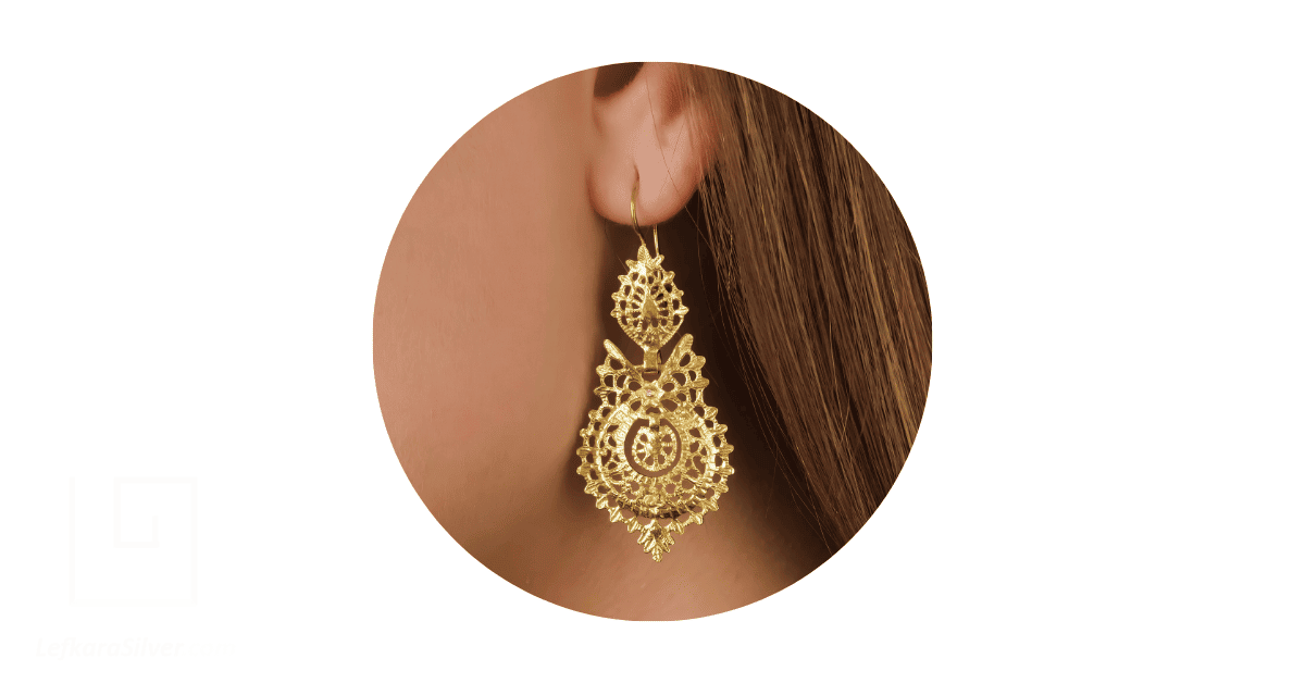 a person's ear adorned with a gold filigree earring.