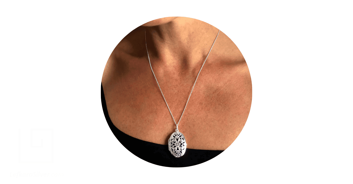 a woman wearing a silver filigree necklace with a locket.