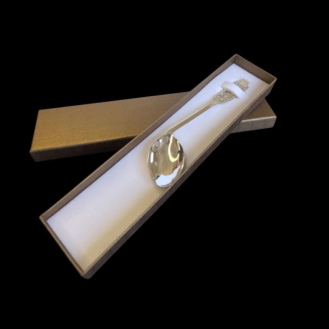 Handmade silver baby feeding spoon with an elongated bowl and lacelike filigree handle, by Lefkara Silver Cyprus.
