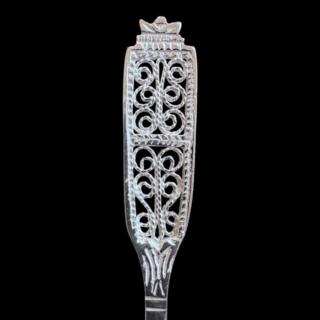 Handmade silver baby feeding spoon with an elongated bowl and lacelike filigree handle, by Lefkara Silver Cyprus.