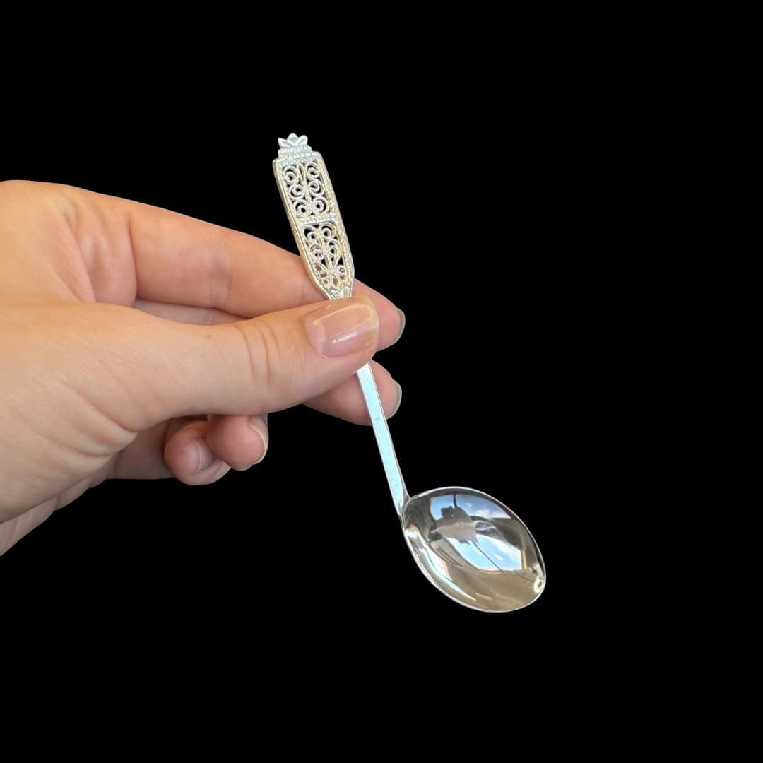 Handmade silver baby feeding spoon with an elongated bowl and lacelike filigree handle, by Lefkara Silver Cyprus.