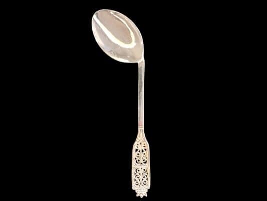 Handmade silver baby feeding spoon with an elongated bowl and lacelike filigree handle, by Lefkara Silver Cyprus.