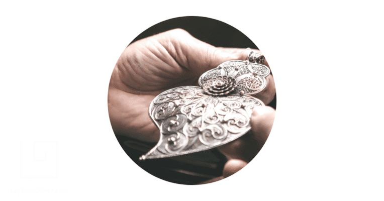 A filigree jeweler holding a filigree pendant.